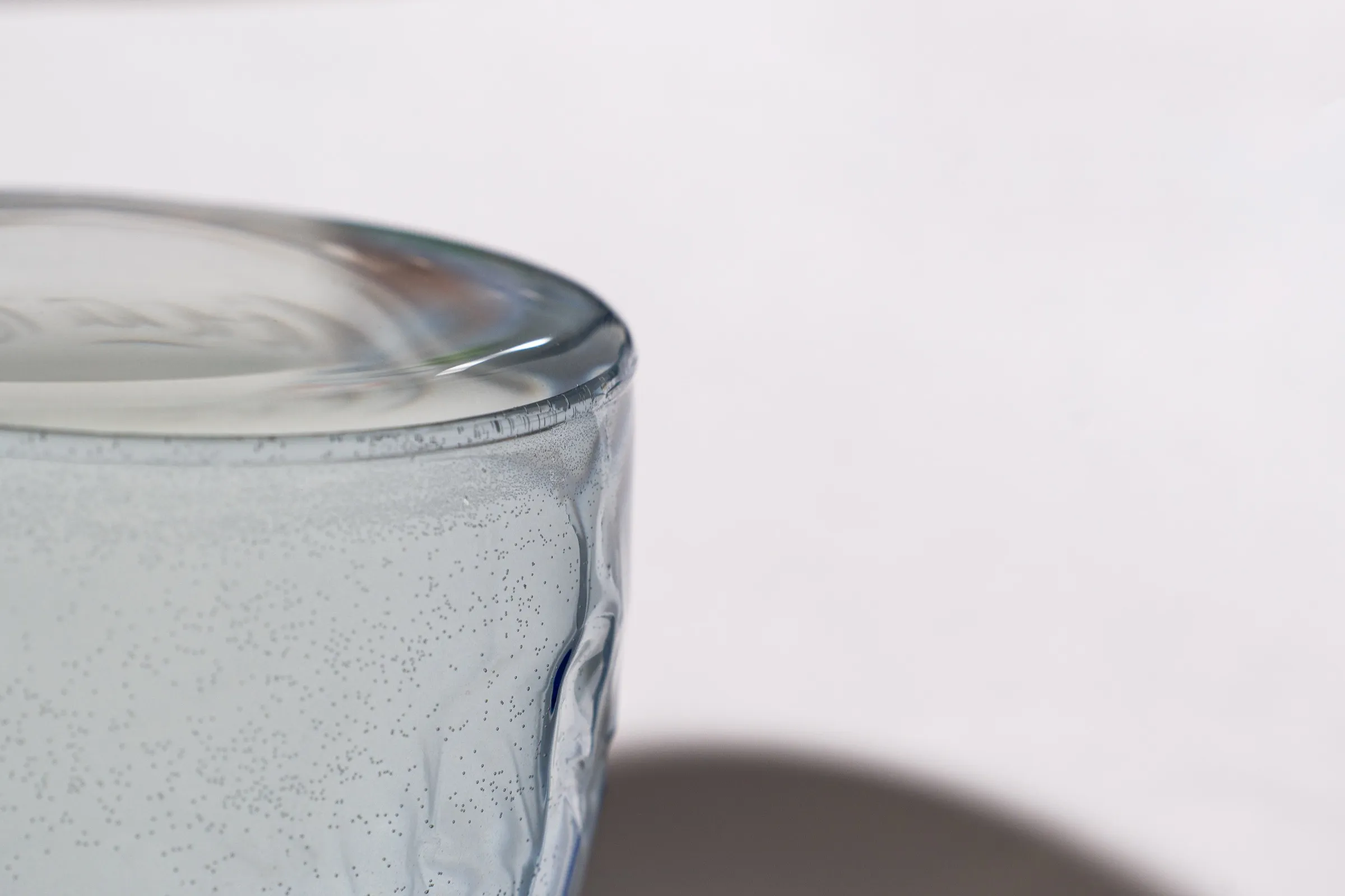 nahaufnahme eines wasserglasrands mit kondenswasser und luftblasen